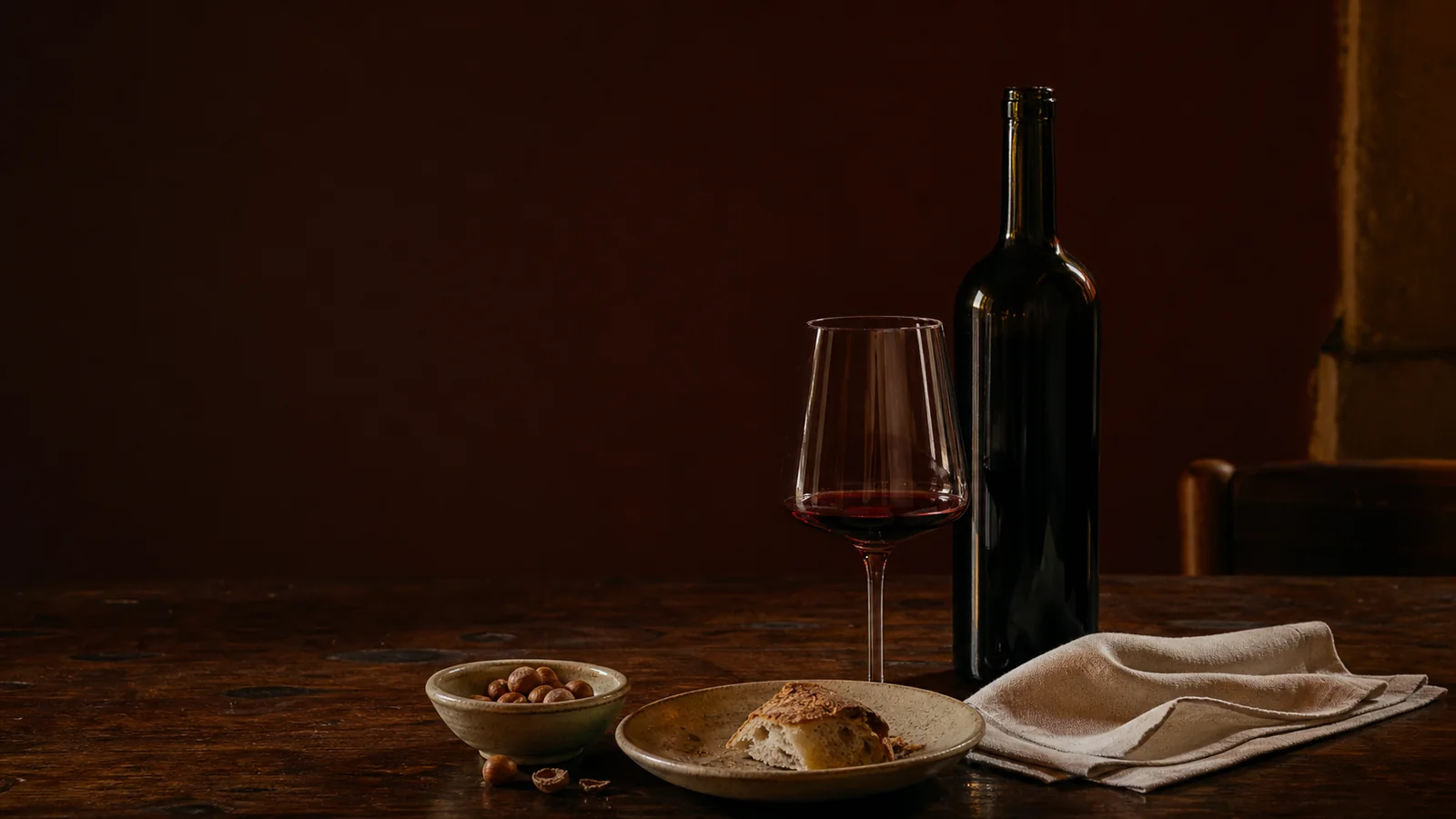 Calice di vino rosso accanto a una bottiglia senza etichetta