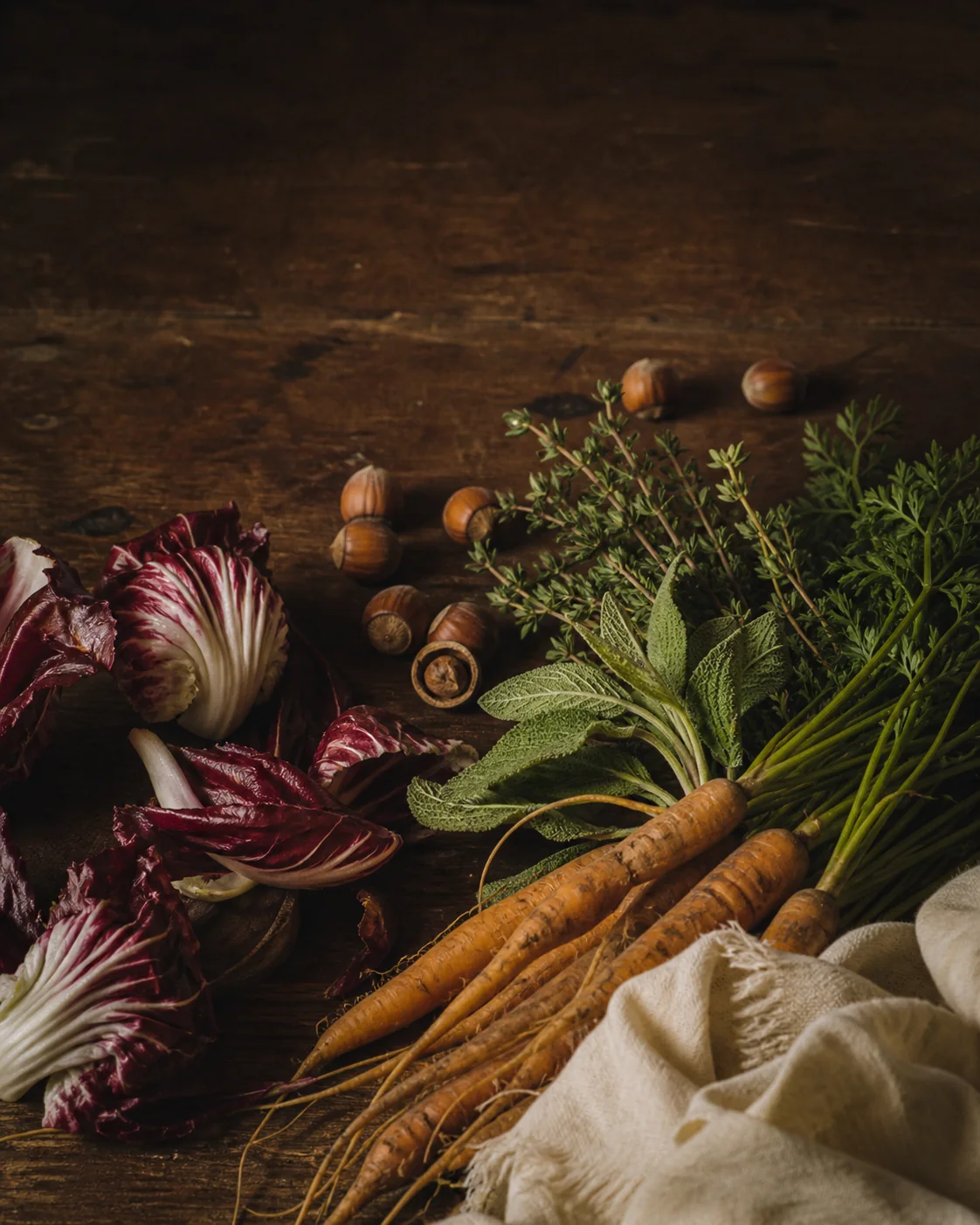 Verdure di stagione, erbe e nocciole su un tavolo di legno